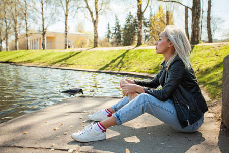 Young woman outdoors. Blonde model in blue denim and black leatherの写真素材