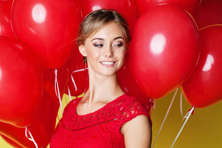 Beautiful young woman face on yellow background with balloons, closeup portraitの写真素材