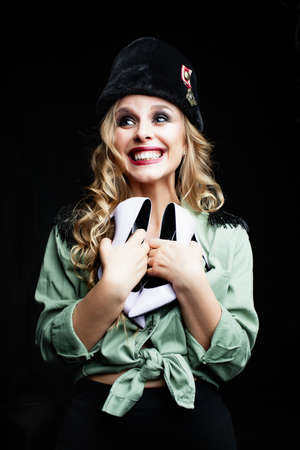 Beauty portrait of young happy woman soldier in military style clothes. Poor girl having fun with new fashionable high heels shoes. Vogue conceptの写真素材