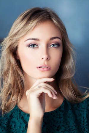 Closeup portrait of cute young woman. Female face on blue backgroundの写真素材