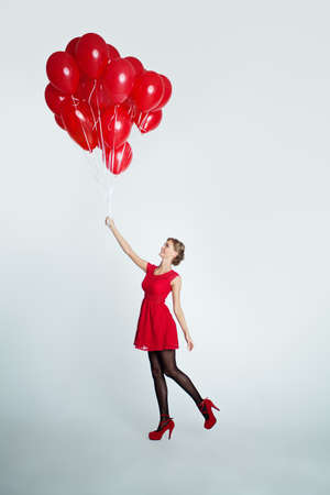 Cute Woman in Red Dress holding Balloons, Holiday Backgroundの写真素材