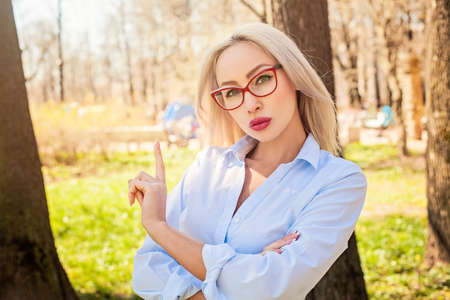 Confident woman in blouse and glasses, outdoors portraitの写真素材