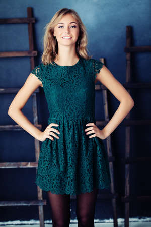 Young fashion model woman in green dress. Cute girl on blue rustik backgroundの写真素材