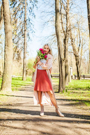 Happy woman model with flowers outdoors. Blonde female model with peonyの写真素材