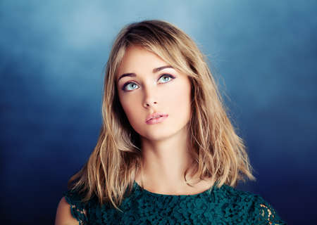 Beautiful young woman looking up on blue backgroundの写真素材