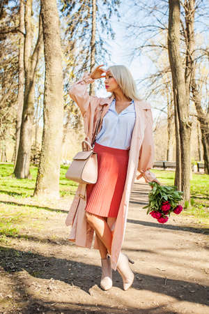Perfect woman with flowers outdoors. Blonde female model with peony waiting in parkの写真素材