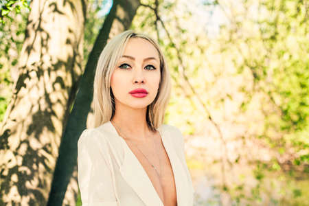 Blonde woman face outdoors. Woman on green leaves backgroundの写真素材