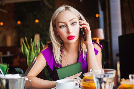 Young woman chatting with smartphone in restaurantの写真素材