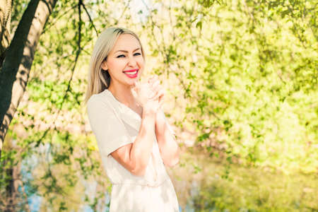 Happy blonde woman having fun outdoors on green foliage leaves backgroundの写真素材