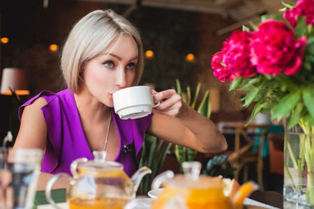 Pretty woman drinking herbal tea in restaurantの写真素材