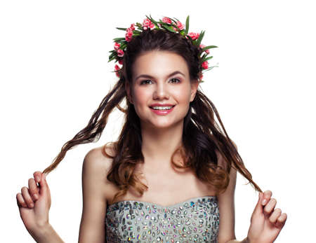 Happy Prom Girl with Perfect Hairstyle and Makeup Isolated on White Background. Young Woman with Flowers in Hairの写真素材