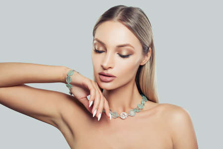 Beautiful Female Face Closeup. Glamorous Fashion Model Woman in Jewelry Necklace and Bracelet. Blonde Hair, Makeup and Accessoriesの写真素材