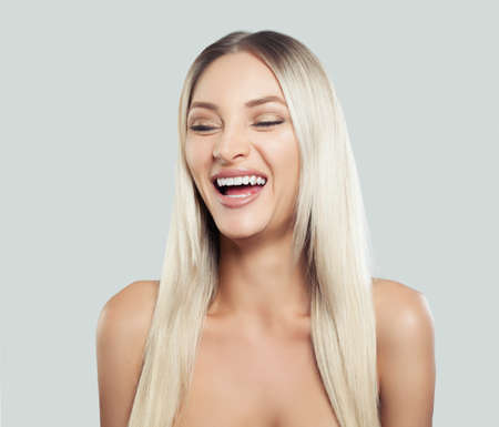 Happy Woman Laughing. Female Model with Long Healthy Blonde Hair on White Background. Expressive facial expressions.の写真素材