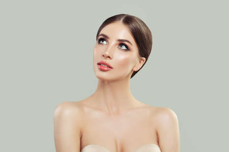 Young woman looking up on background with copy space. Beautiful model with healthy skin. Facial treatment, skincare, cosmetology, beauty and spaの写真素材