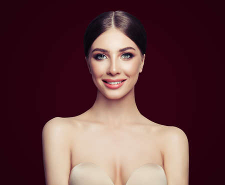 Perfect young woman model smiling, fashion beauty portrait on dark red backgroundの写真素材