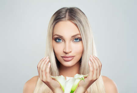Beautiful young woman with clean fresh skin, blonde hair and lily flowers.の写真素材