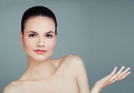 Healthy female model with empty copy space on the open hand on blue background. Plastic surgery, cosmetology, skincare and wellness concept. Presenting your productの写真素材