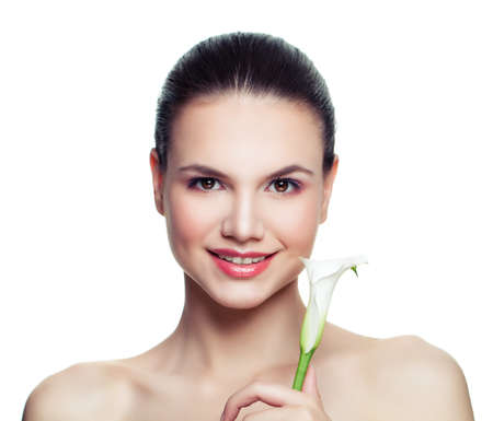 Smiling woman with white flower isolated on white background. Beautiful female model face with clear fresh skin. Facial treatment, cosmetology, beauty, skincare and spa conceptの写真素材