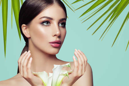 Spa woman with healthy skin, manicured hands and white flowers. Facial treatment, cosmetology and spaの写真素材