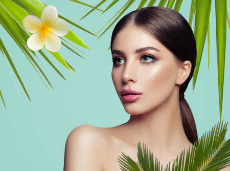 Spa woman with healthy skin and tropical leaves and flowers on blue background, spa beautyの写真素材