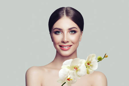 Happy woman spa model with healthy skin, cute smile and orchid flowers. Facial treatment, cosmetology, beauty salon, skin care and spaの写真素材