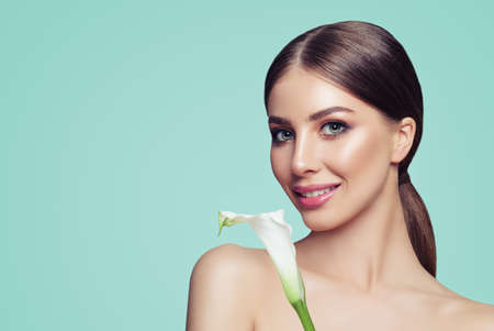 Beautiful Woman Face. Model Girl with Makeup and Flower on Blue Backgroundの写真素材