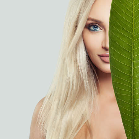 Young perfect female face. Beautiful blonde woman with healthy skin and green leaf. Natural beautyの写真素材