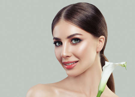 Cheerful woman with healthy skin and white calla flower. Facial treatment, cosmetology, beauty salon, skin care and spaの写真素材