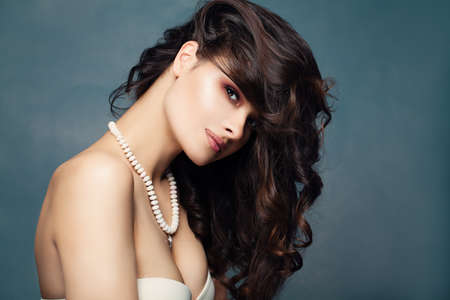 Fashion portrait of cute brunette woman. Sexy female model with dark curly hair and necklaceの写真素材