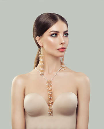 Stylish woman with fashion jewelry portrait. Jewelry for woman, golden necklace and earrings with white pearls. Beauty and accessories.の写真素材