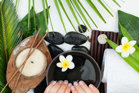 Beautiful female hands with flowers, green leaves, towel. Spa manicure.の写真素材