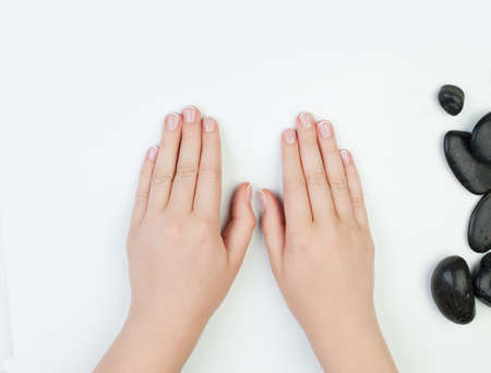 Beautiful female hands and black stones on white background. Concept on Manicure tableの写真素材