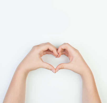 Female hands with heart shape on white background. Manicure conceptの写真素材