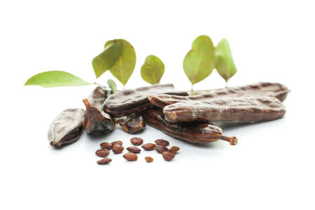 Carob bean on white. Healthy organic sweet carob pods with seeds and leaves, healthy eating and food background.の写真素材