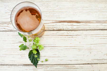 Beer glass with beer hops leaves and cones on vintage wooden table background with copy space, top viewの写真素材