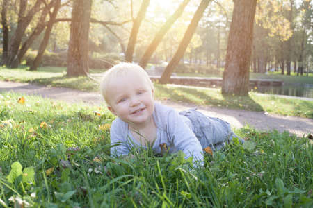Kid lying on the green grass outdoor. Little child boy portraitの写真素材