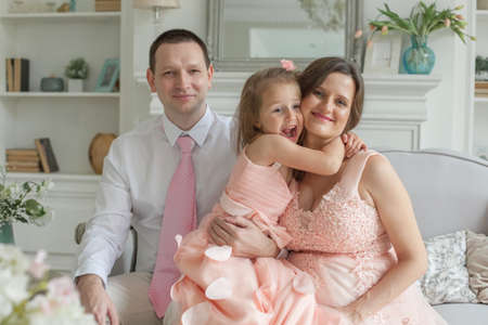 Happy family hugging and smiling. Mother, father, child daughter at homeの写真素材