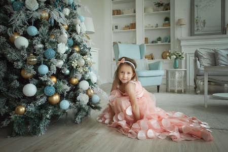 Cheerful child girl with Christmas tree at homeの写真素材