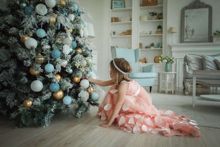 Little child girl with Christmas tree at homeの写真素材