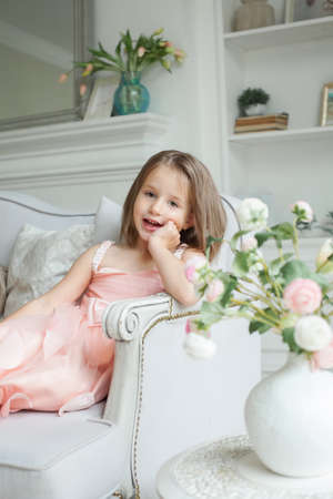 Happy little girl in pink dress having fun at homeの写真素材