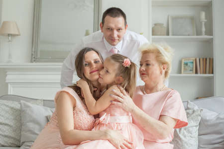 Happy family. Grandmother and mother, daughter, father. Older woman, man, pregnant adult woman and child girlの写真素材