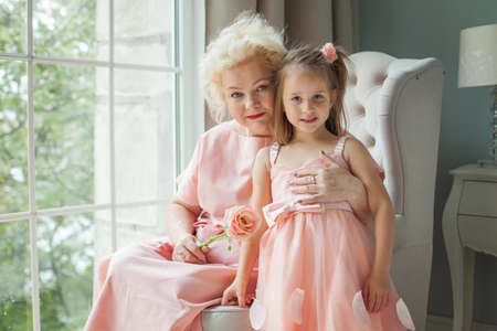 Grandmother and granddaughter hugging and smiling. Older woman and child girl at homeの写真素材