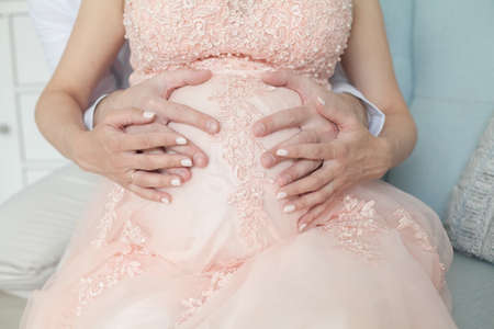Parental love and care concept. Parents hands on the belly of the pregnant mother.の写真素材