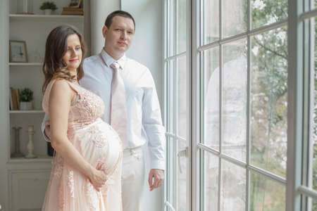 Young couple expecting baby standing together indoorsの写真素材