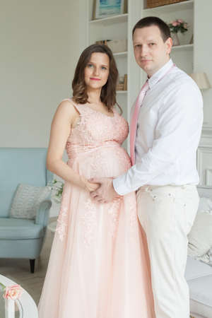 Happy man hugging his pregnant wife at home. Pregnancy and people conceptの写真素材
