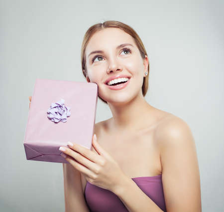 Attractive woman with present and cute smile on white background. Female model looking upの写真素材