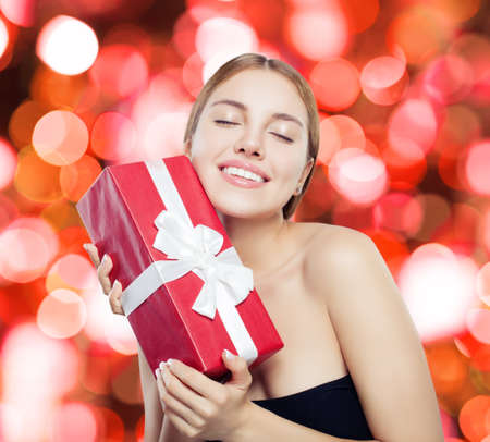 Happy woman with red gift box on party glitter backgroundの写真素材