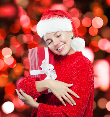 Christmas woman portrait. Beautiful girl with gift on bokeh backgroundの写真素材