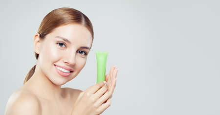 Young smiling woman with moisturizer cream tubeの写真素材