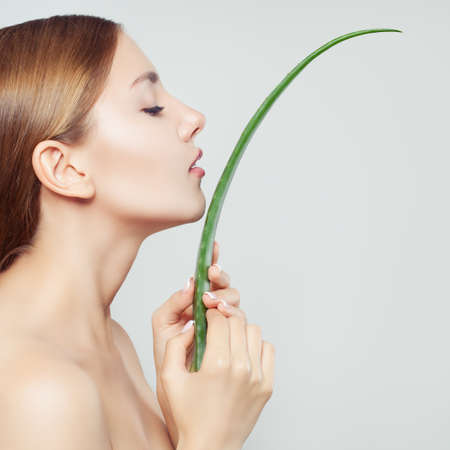 Beautiful woman face and aloe vera leaf, closeup portrait. Skincare conceptの写真素材